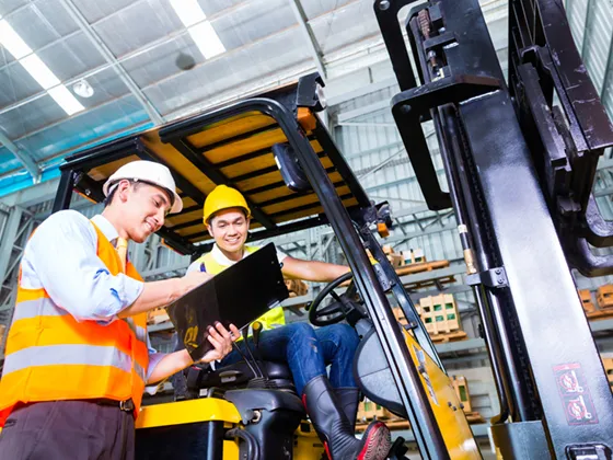 Engineer performing an assessment of a worker driving a forklift in the warehouse of a large e-commerce company.