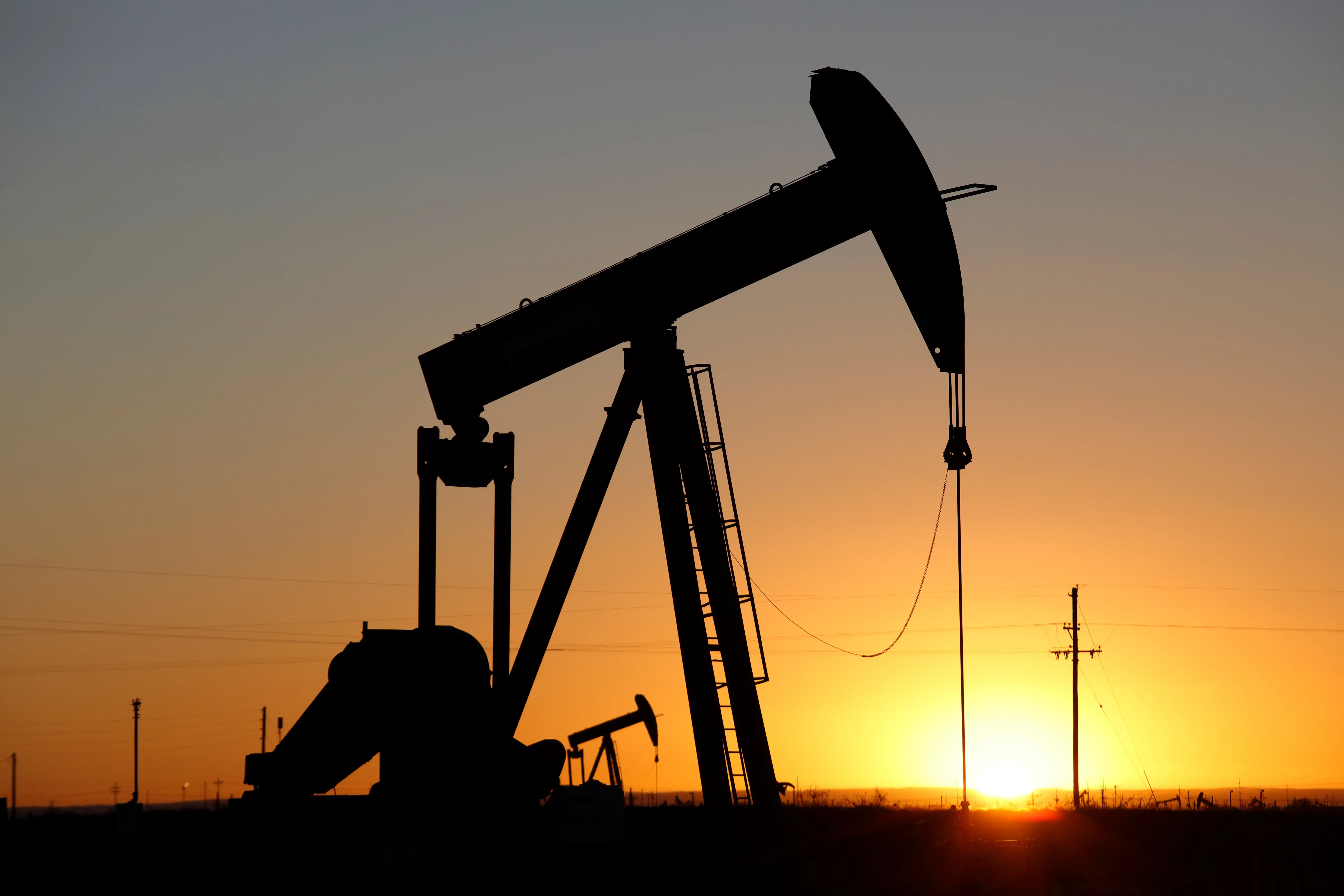 The silhouette of a mineral resources pumpjack operating at sunset.