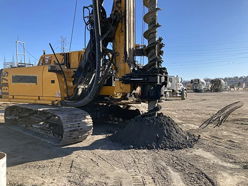 Excavation drill drilling into the ground on site at a power plant, where Apex conducted a comprehensive hazardous materials survey.