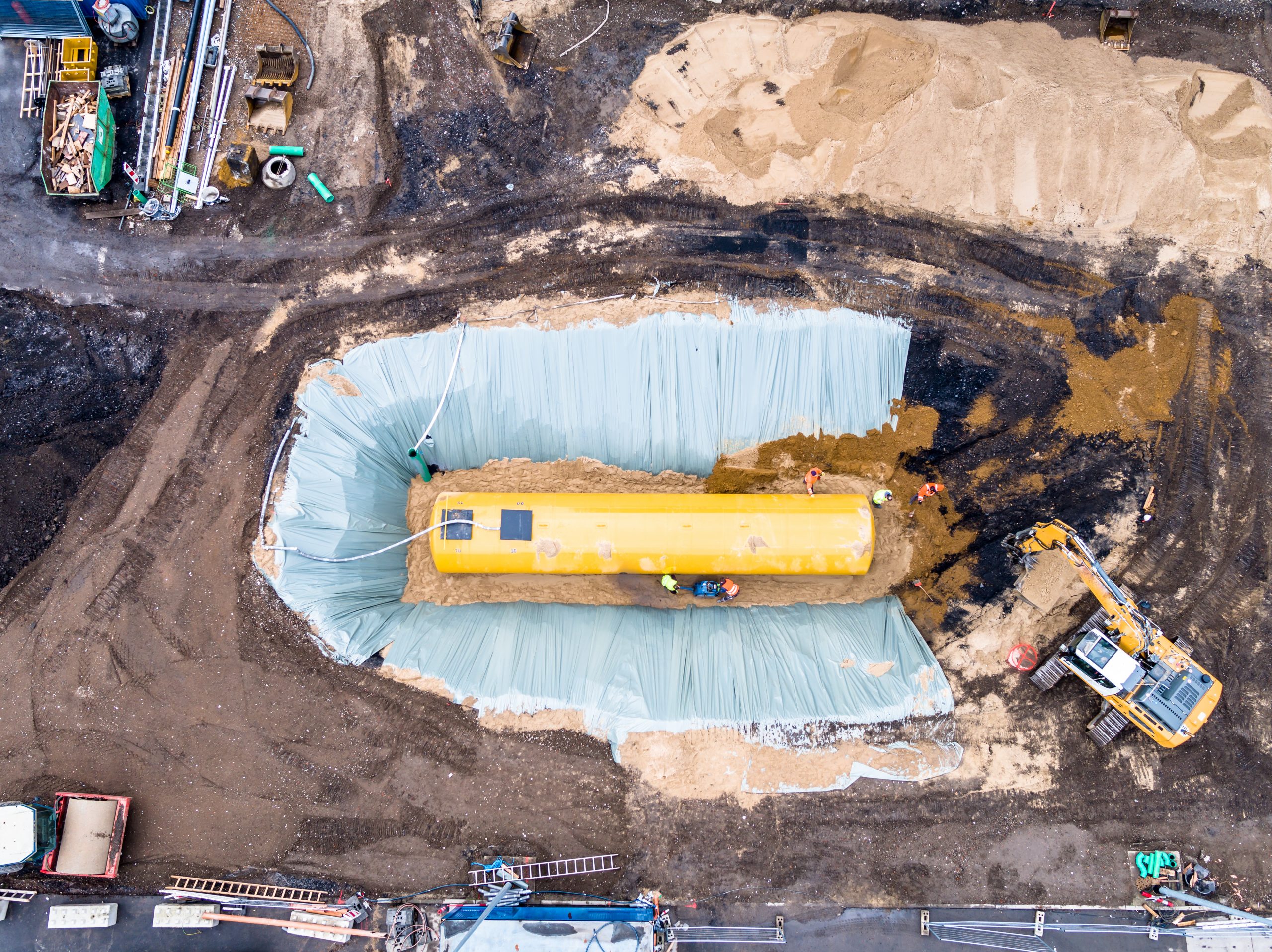 Worker installing a huge fuel tank Worker installing a huge underground fuel tank, aerial