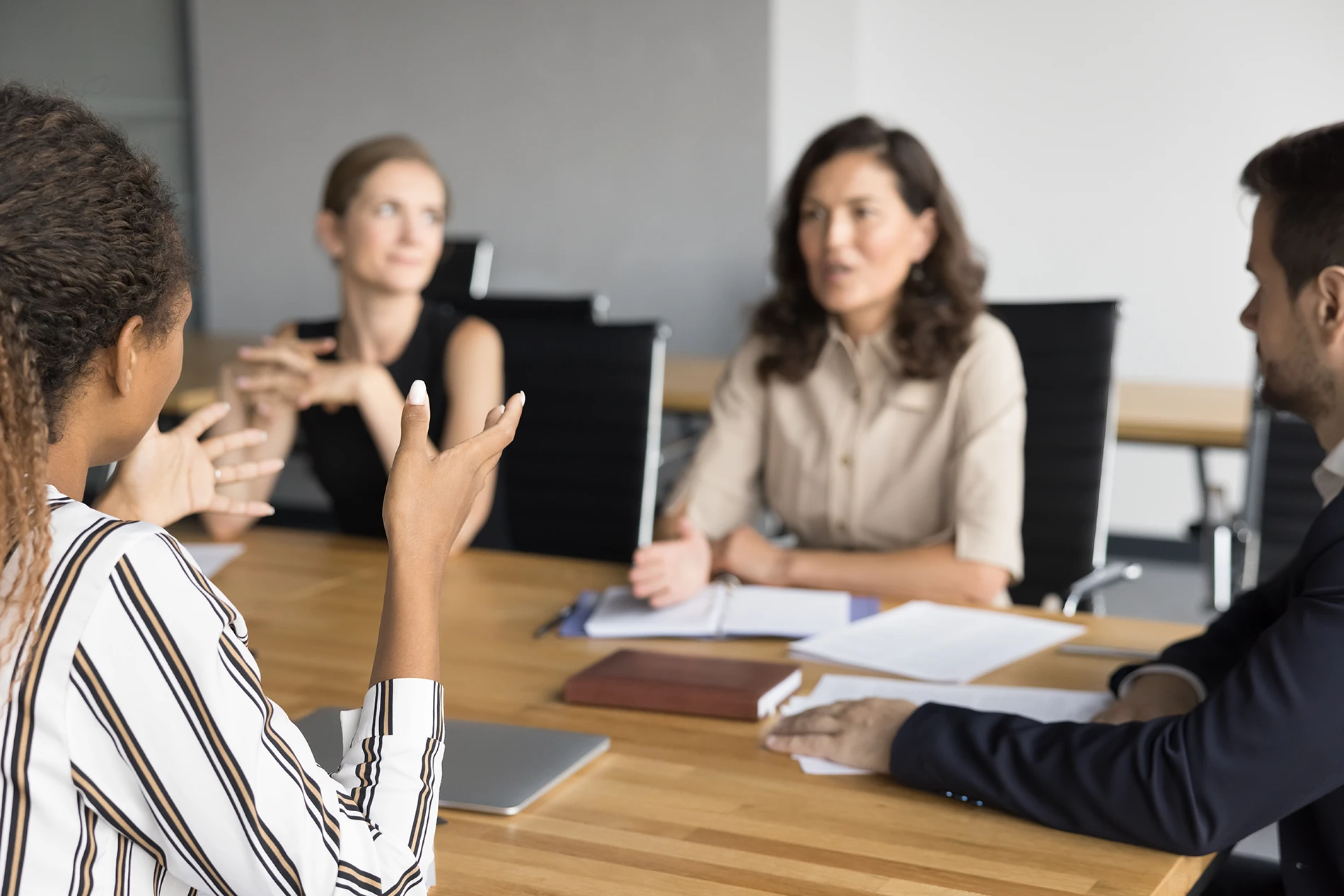 A group of people at a table holding a meeting to assess the goals for the vision, mission, values, and culture of the business.