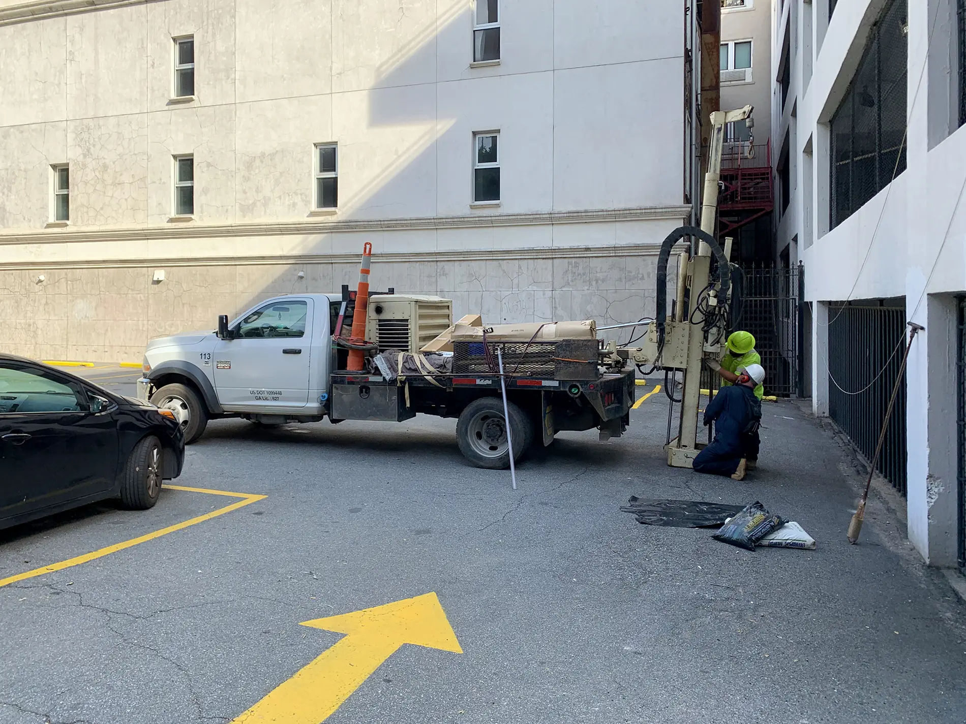 Apex employees using boring machinery for soil and groundwater sampling during a voluntary remediation program at a mixed urban high-rise and industrial area developed with a parking garage and asphalt parking lot in Atlanta, GA.