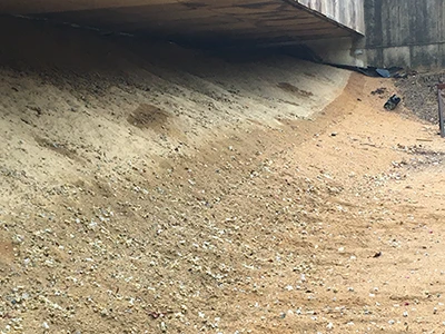 Sand congested with debris including shotgun wads and lead bullets prior to firing range berm refurbishment.