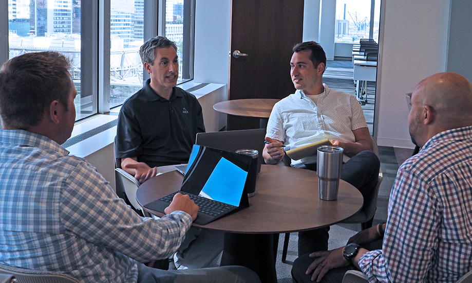 vision-3 Apex employees in discussion around a table in an office
